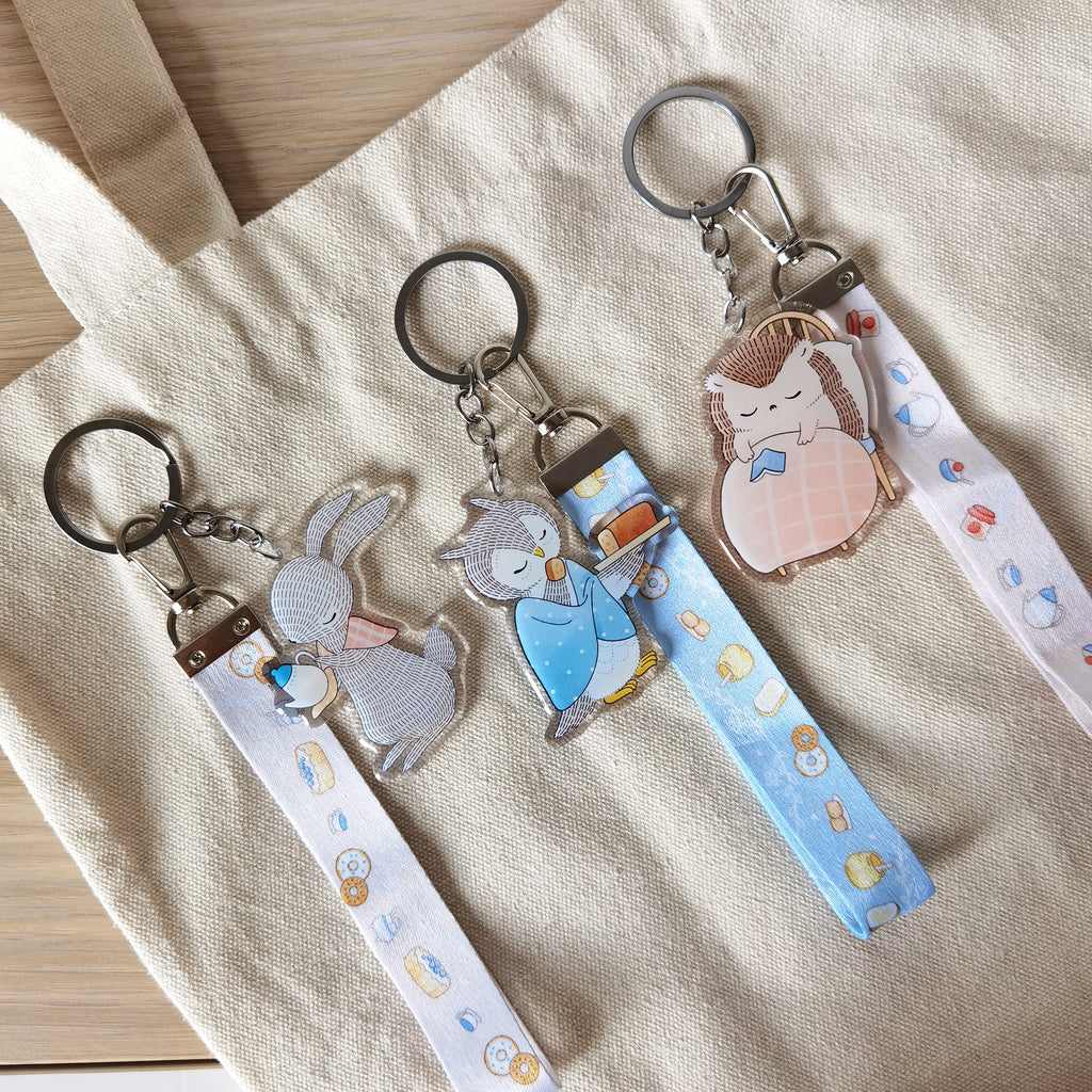 Adorable acrylic key charm featuring a rabbit, owl, and hedgehog, paired with tea-time dessert lanyard. A whimsical accessory for bags or keys.
