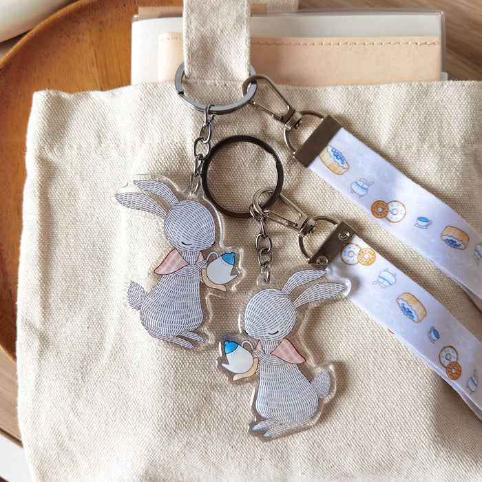 Cute rabbit teapot key charm with matching lanyard of illustrated blueberry pie, tea, and sugar. A whimsical accessory for bags or keys.