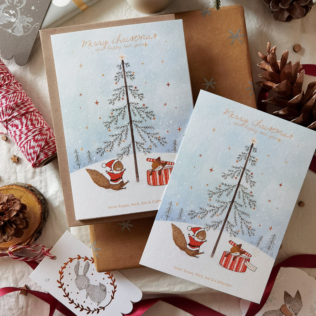 Illustrated holiday notecard with personalized names, featuring a squirrel and a fox in a delightful Christmas box surprise.