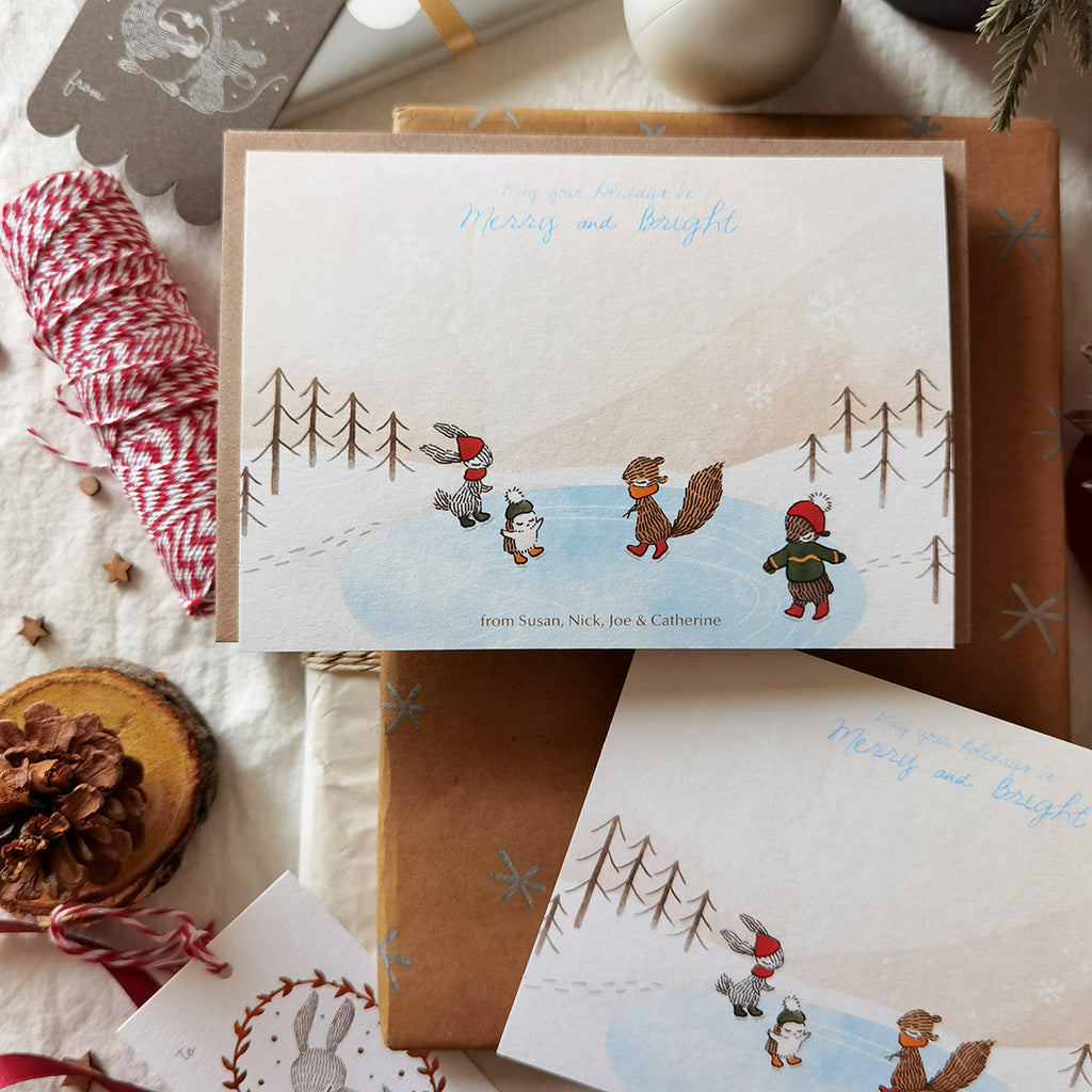 Illustrated ice skating woodland animals on a flat notecard for joyful holiday greetings, personalized names at the bottom.