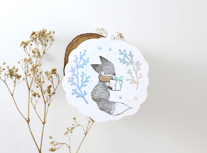 Holographic Foil Christmas Holiday Gift Tags - Fox & Christmas Gift - winter berries elegantly printed in holographic foil, whimsical fox illustration holding a gift box, scalloped custom die-cut shape, embellished with cotton twine.