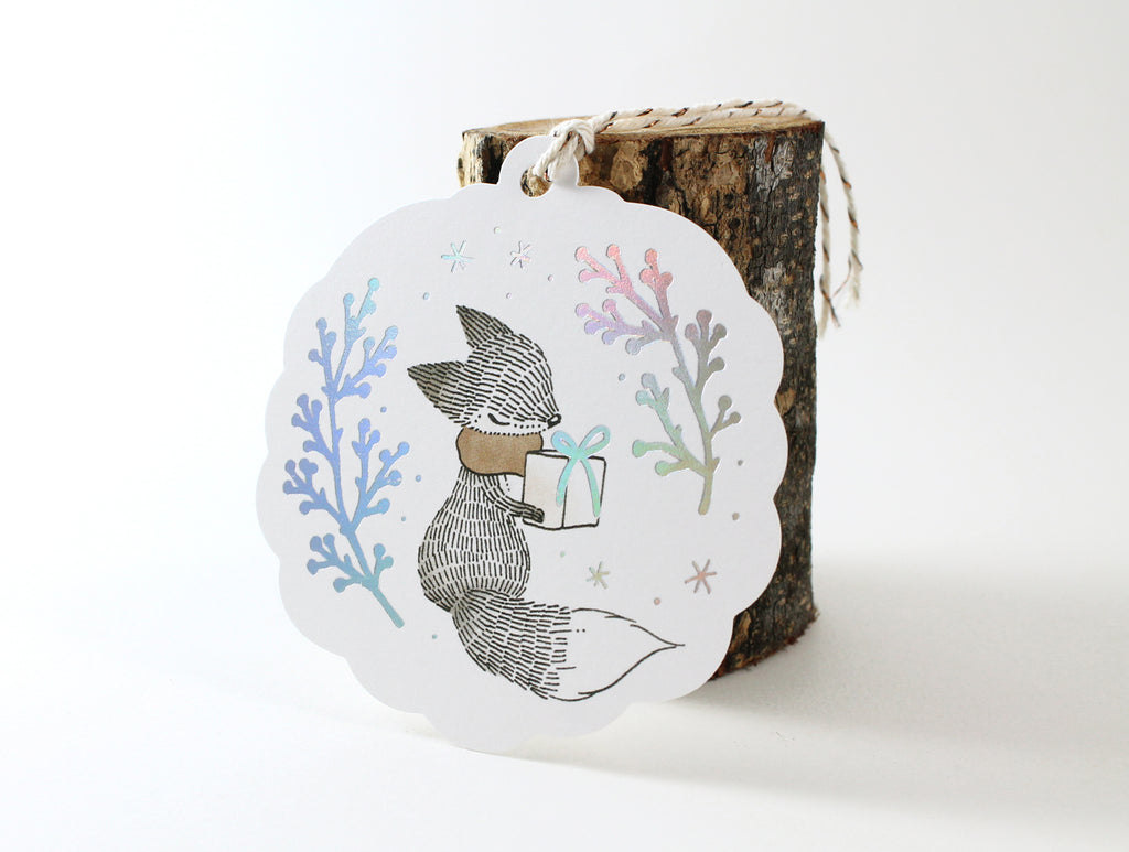 Holographic Foil Christmas Holiday Gift Tags - Fox & Christmas Gift - winter berries elegantly printed in holographic foil, whimsical fox illustration holding a gift box, scalloped custom die-cut shape, embellished with cotton twine.