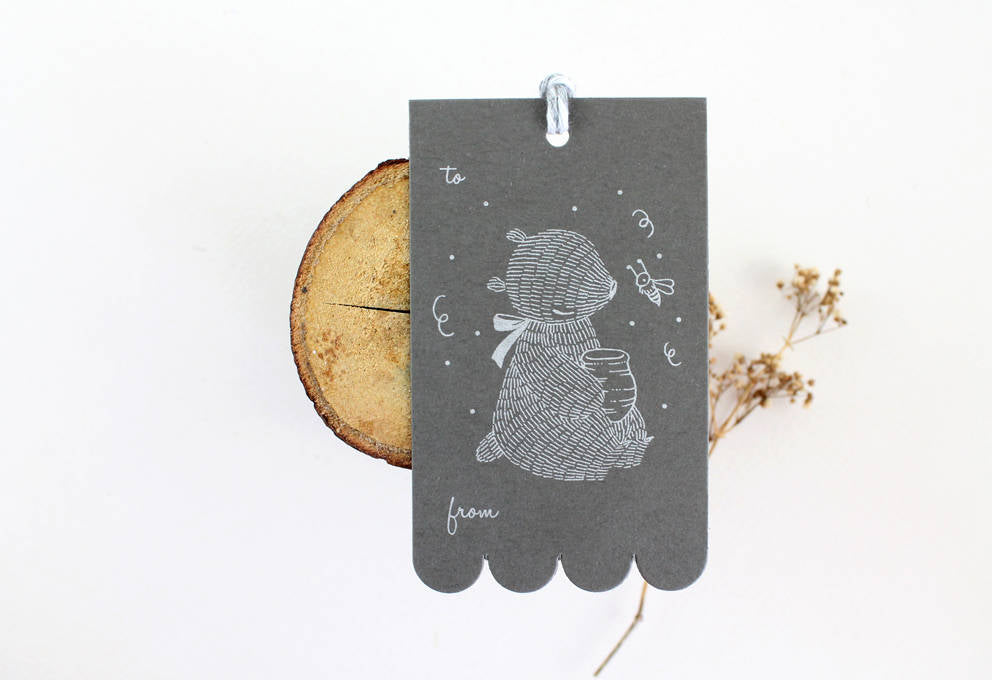 Rectangular gift tag with Bear & Honeypot design, silver ink on sombre grey cardstock. Scalloped edge on one side. Ideal for birthdays & showers.