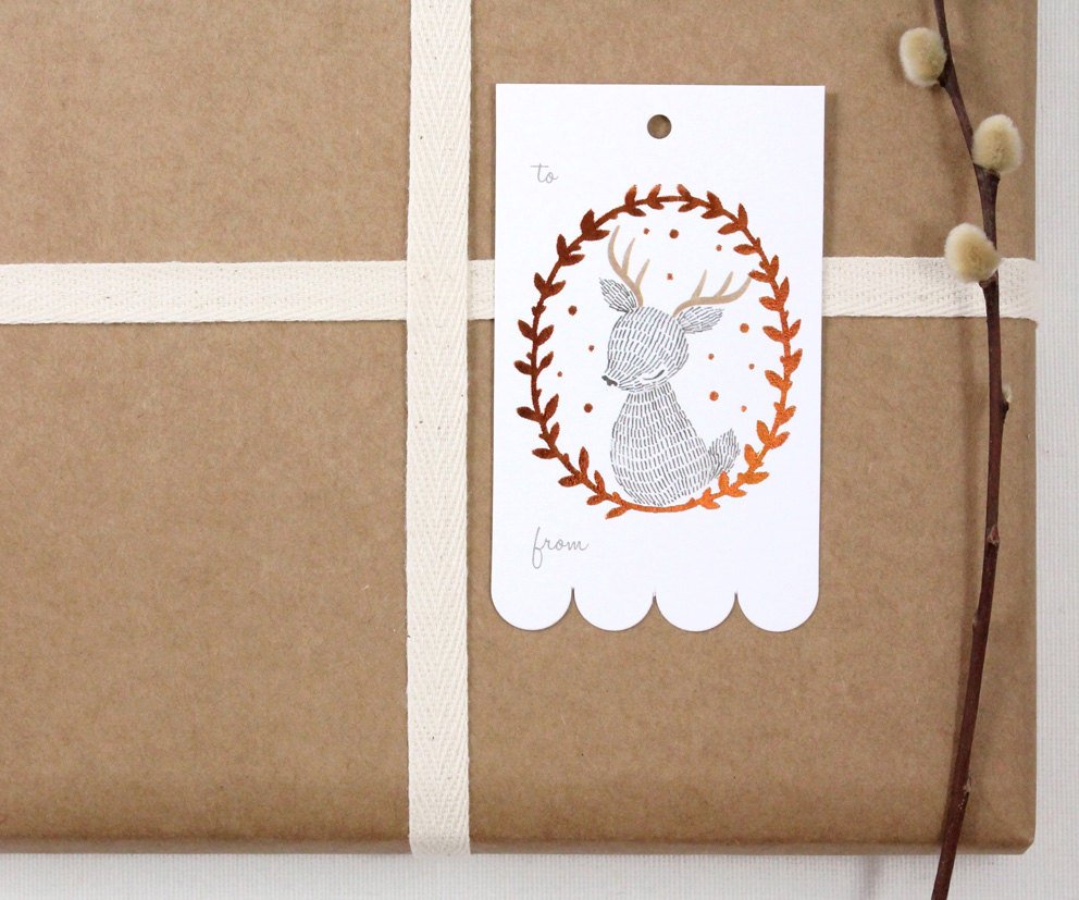 Rectangular Christmas gift tag with illustrated reindeer in shimmering copper foil wreath on sturdy cardstock. Scalloped edge on one side. Ideal for holiday gifting.